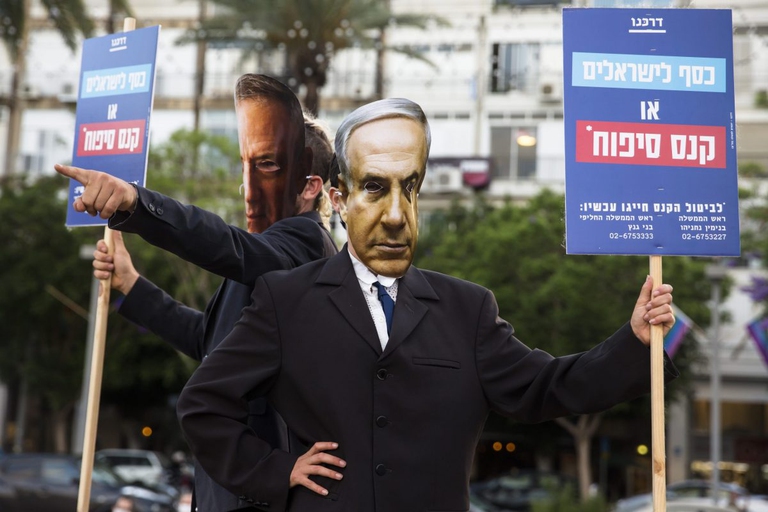 Manifestanti con le maschere del premier Benjamin Prime Minister Benjamin Netanyahu e del ministro della Difesa Benny Gantz