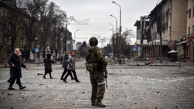 Civili di fronte ad un soldato nella città di Mariupol, in Ucraina