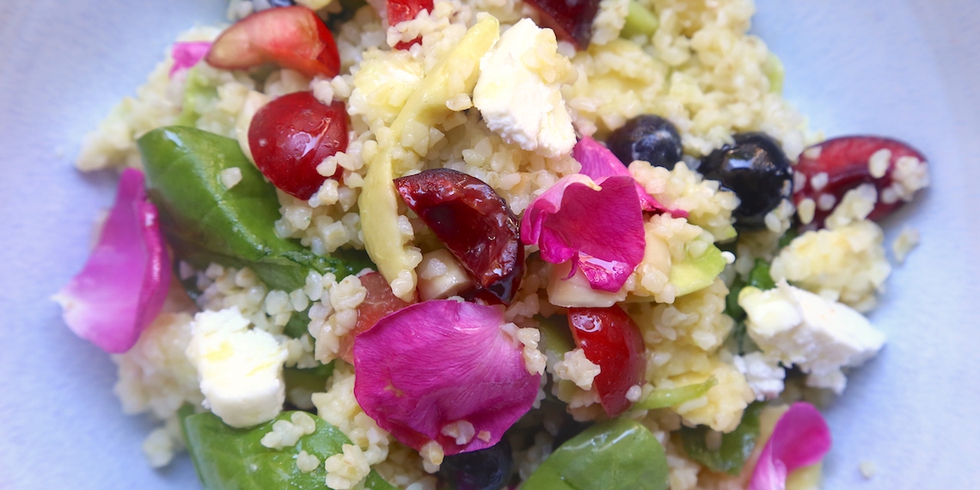 Insalata di bulgur con frutti, fiori, foglie e caprino