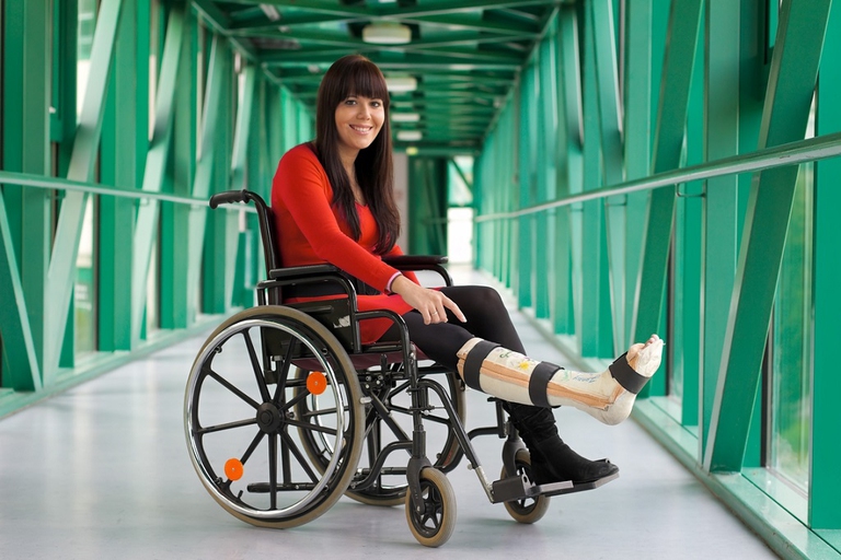 a young woman with a broken leg. leg in plaster and wheelchair