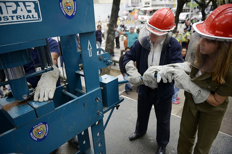 Police destroy handguns by means of an industrial press during a weapon destruction operation in Caracas on May 20, 2013. AFP PHOTO/Leo RAMIREZ (Photo credit should read LEO RAMIREZ/AFP/Getty Images)
