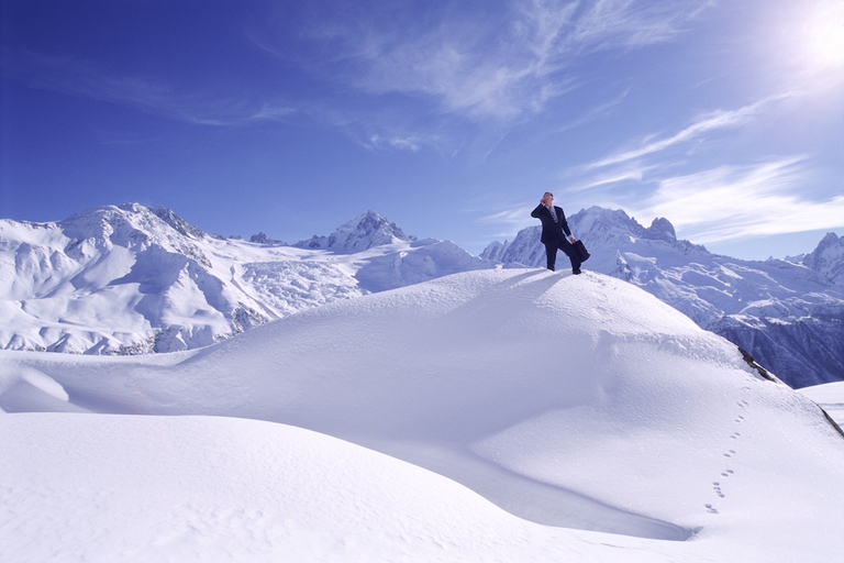 Businessman outdoors on snowy mountain using cellular phone