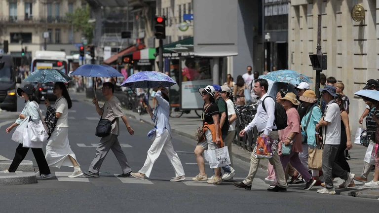 Turisti si proteggono dal caldo estremo con degli ombrelli a Parigi, il 23 giugno 2026
