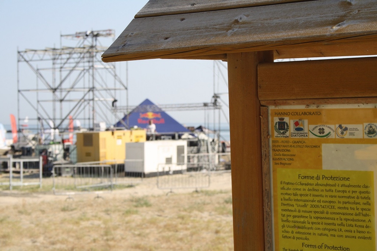 Pannello illustrativo sul fratino, sullo sfondo il palco degli X Masters