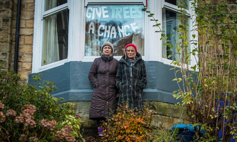 Due signore davanti ad un cartello con le parole di protesta "Give Trees a chance".