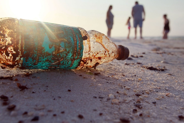 Una bottiglia di plastica in primo piano su una spiaggia in riva al mare. 