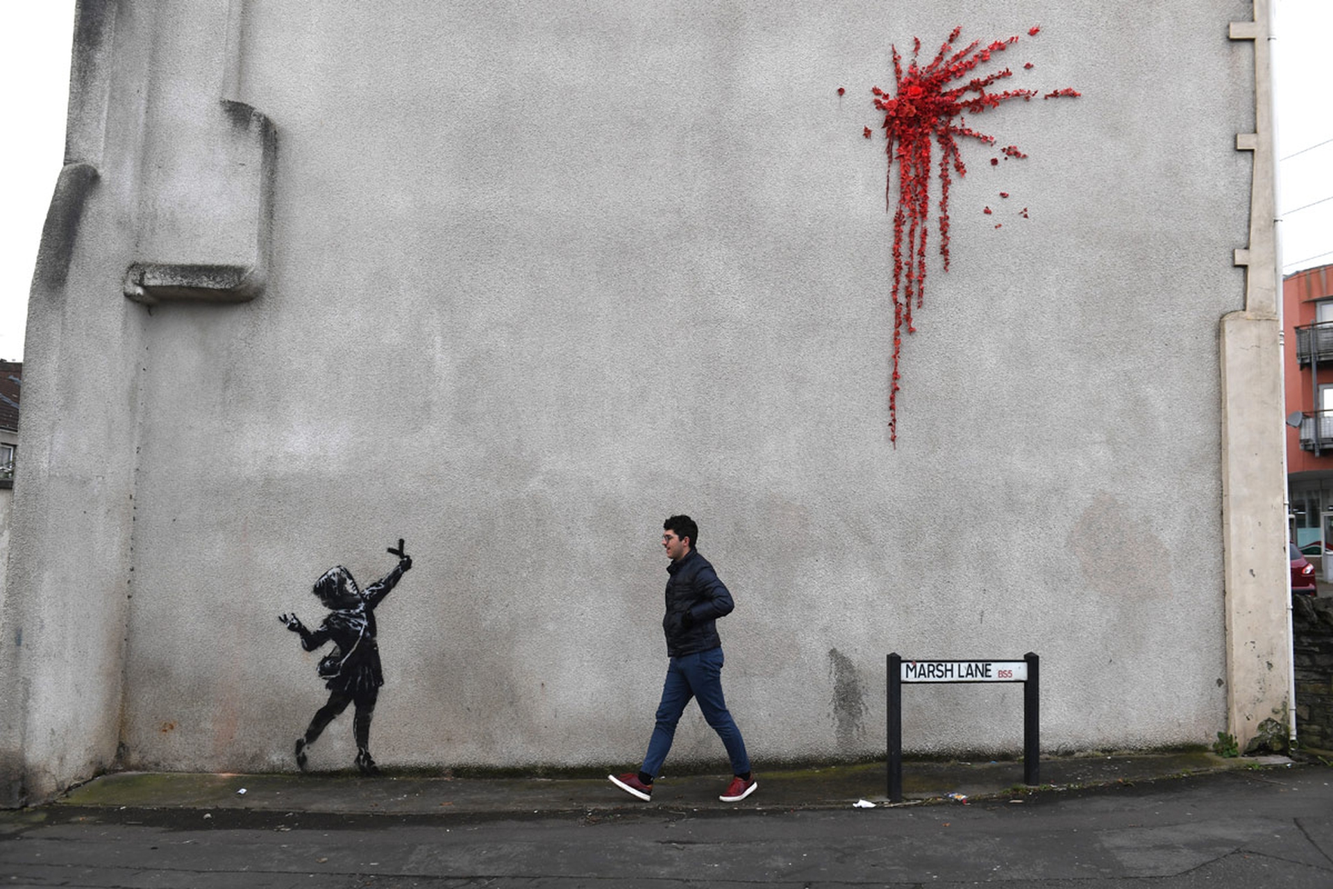Una persona cammina davanti al murales di San Valentino di Banksy
