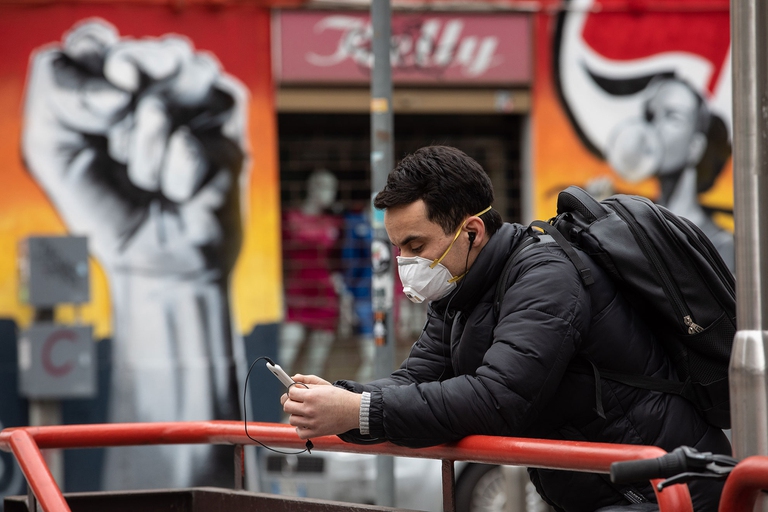 persona appoggiata a metro legge su smartphone