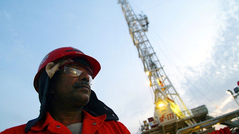 An oil worker walks past a ChevronTexaco drilling platform near the Saudi Arabian border © Joe Raedle/Getty Images