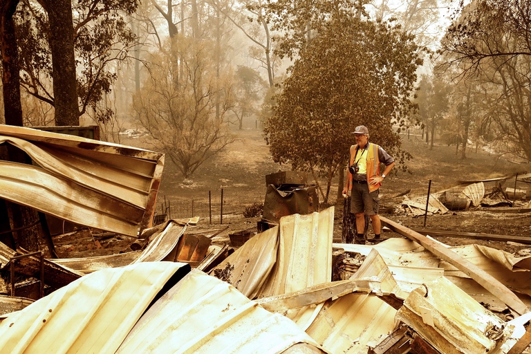 Australian man standing in front of the ruins of his property
