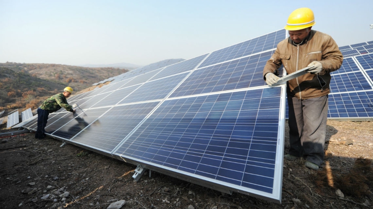 Operai al lavoro in una centrale solare in Cina. Foto via  VCG/VCG Getty Images.