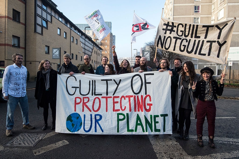 Defendants pose behind a banner outside Court before appearing on a charge of wilful obstruction after blocking a road near Heathrow Airport in protest at climate change on December 2016 in London, England. © Carl Court/Getty Images