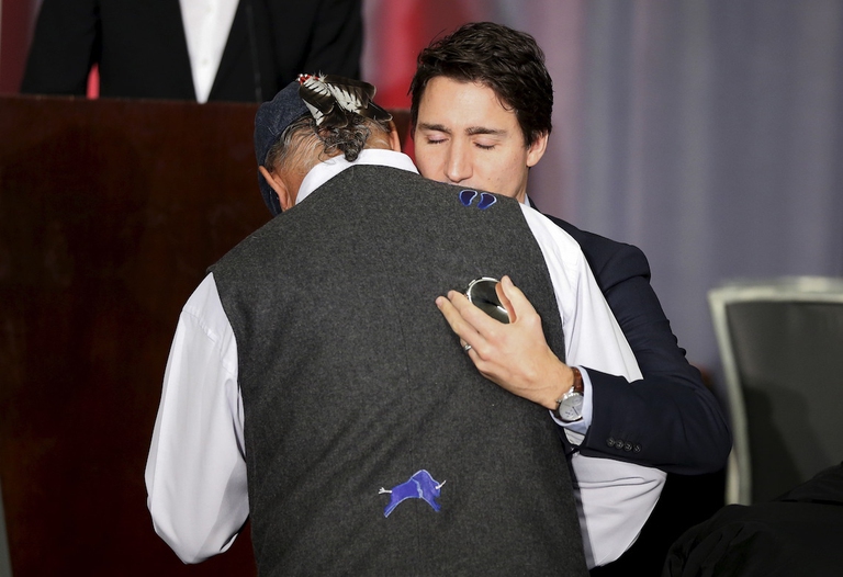 Justin Trudeau (right) hugs residential school survivor Eugene Arcand during the release of the Truth and Reconciliation Commission's final report in December 2015 © Chris Wattie/Reuters