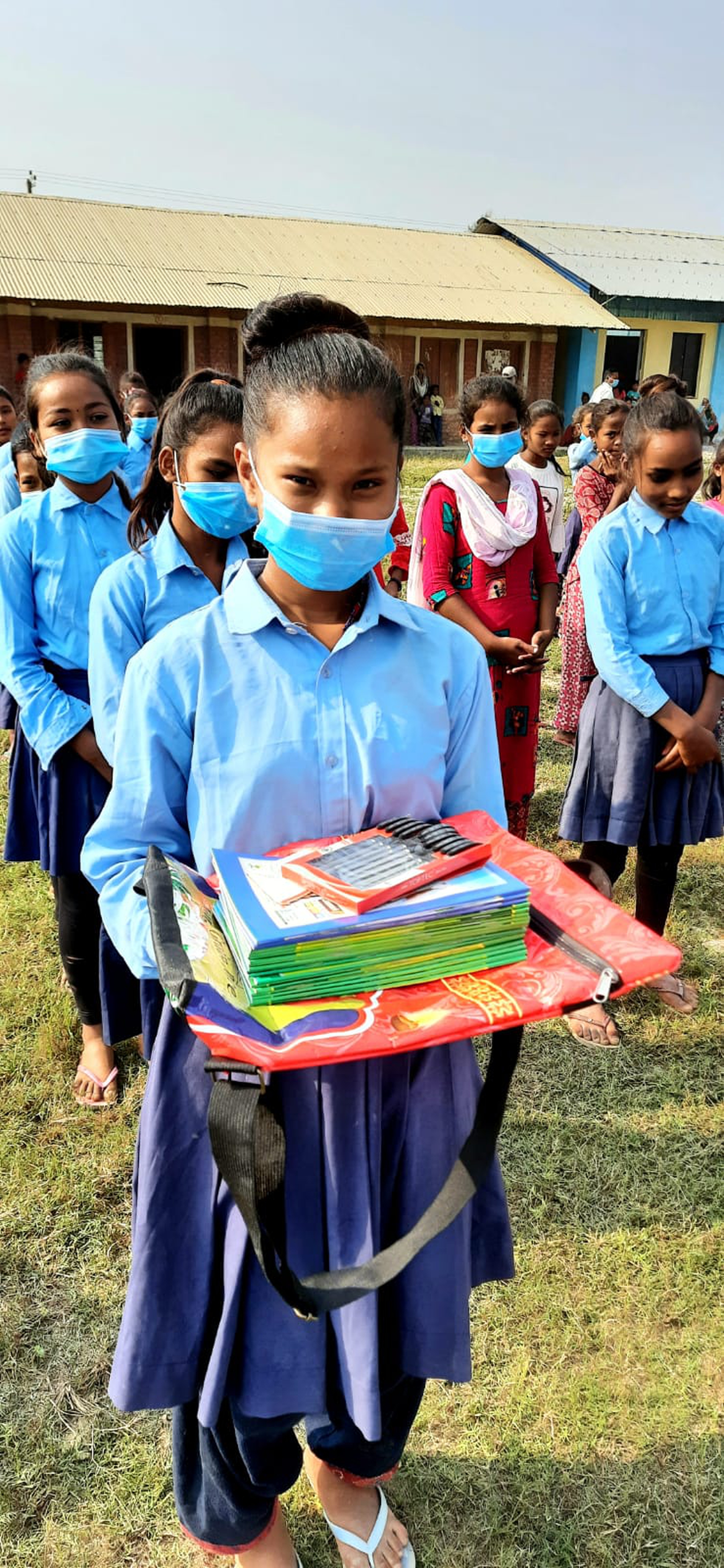 A smiling school girl under the covid mask is clearly happy to recieve the neccesary school supplies and equpiment offered by Gokul Subedi and Prakriiti Mainali. The pandemic has hit areas of rural Nepal the hardest.