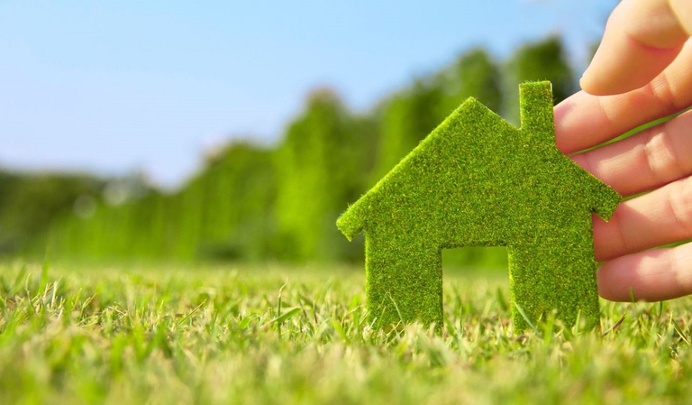 hand holding eco house icon in nature