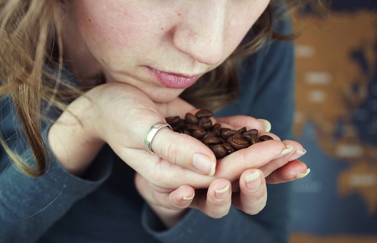 Donna annusa chicchi di caffè tostati