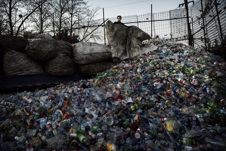 Un lavoratore cinese scarica le bottiglie di plastica da riciclare