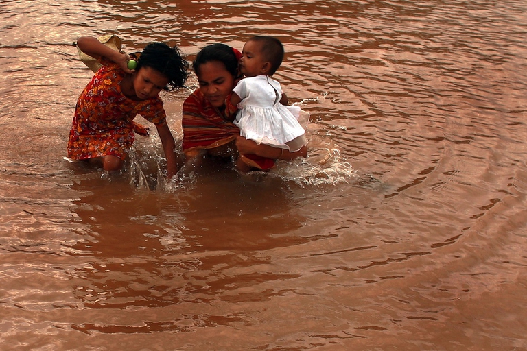 Una donna coi i figli durante un'alluvione in Bangladesh