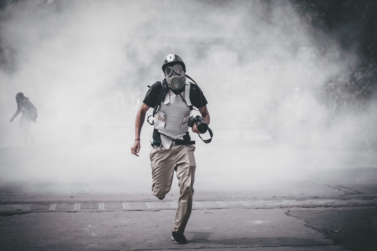 A protester runs from tear gas fired by the Venezuelan national guard during an anti-government demonstration in 2017 in Caracas, Venezuela. © Enphoque