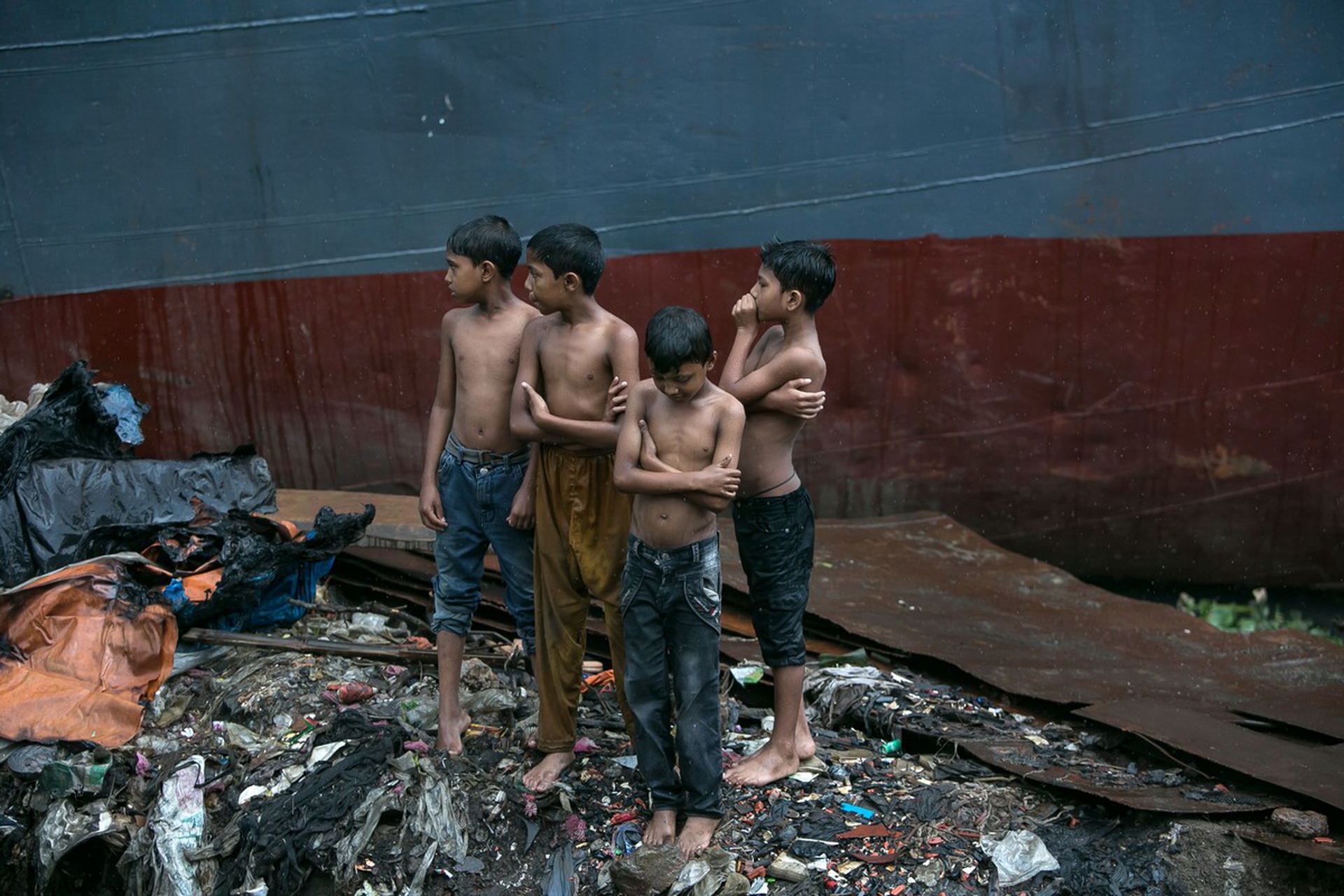 Ragazzini aspettano su un cumulo di rifiuti in Bangladesh