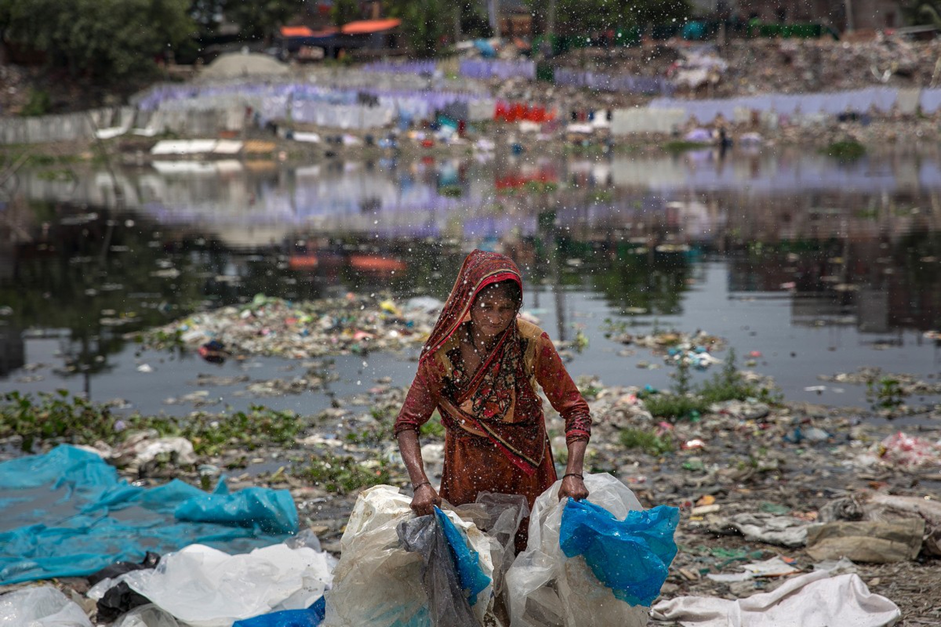Ragazza lava della plastica in un fiume in Bangladesh