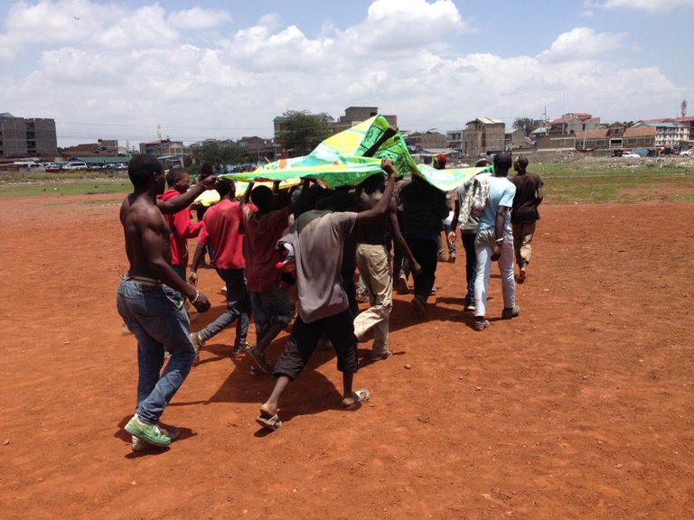 Il gruppo di ragazzi di Carnival!Nairobi simula un matatu in corsa con il tessuto appena dipinto © Cherimus 
