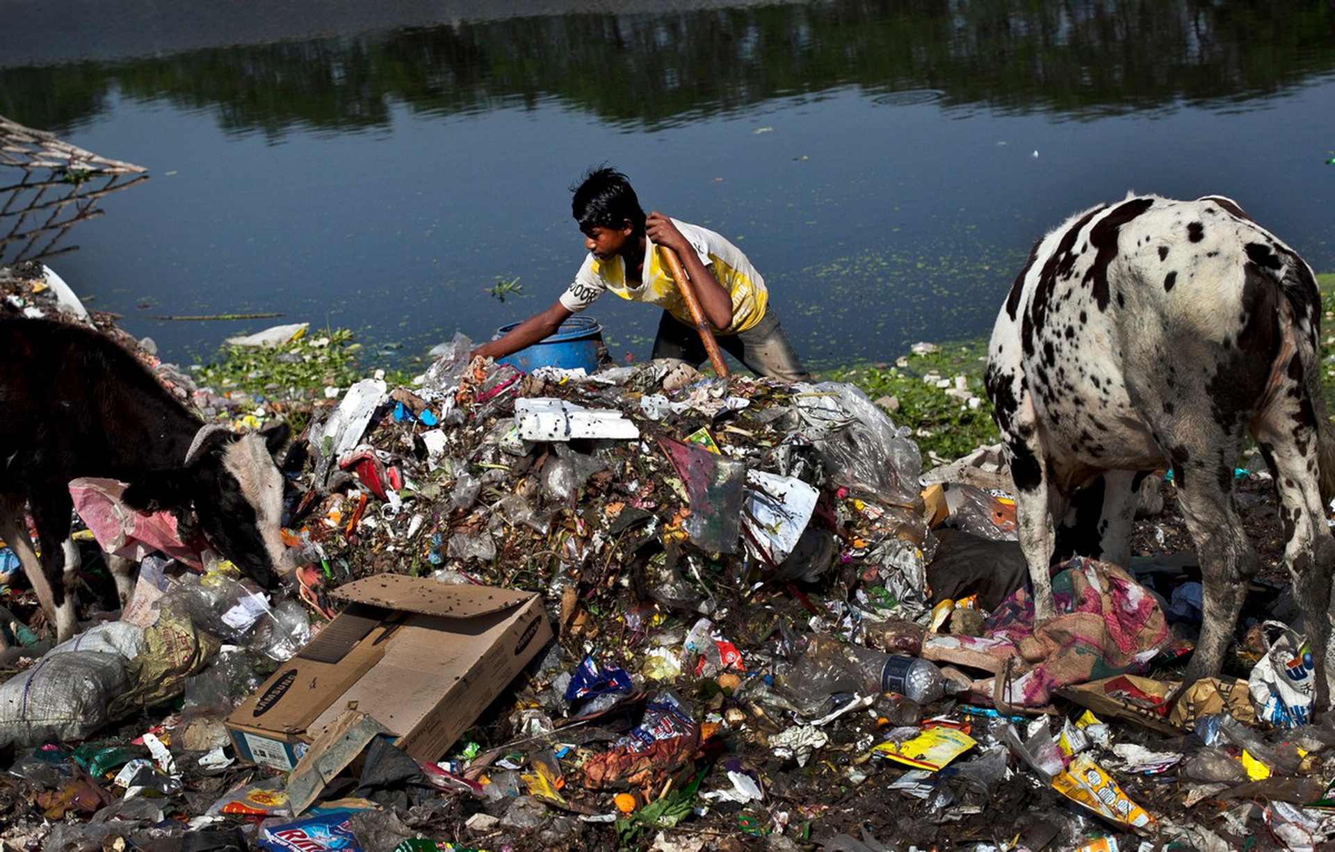 Ragazzo in Bangladesh su un mucchio di rifiuti di plastica