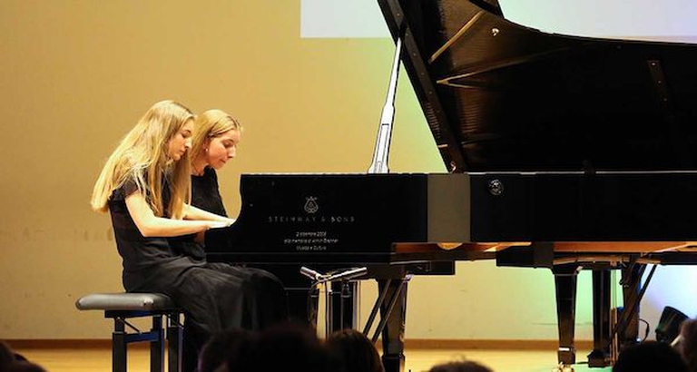 Maria Adele e Caterina Zampa sedute al pianoforte eseguono un quattro mani.