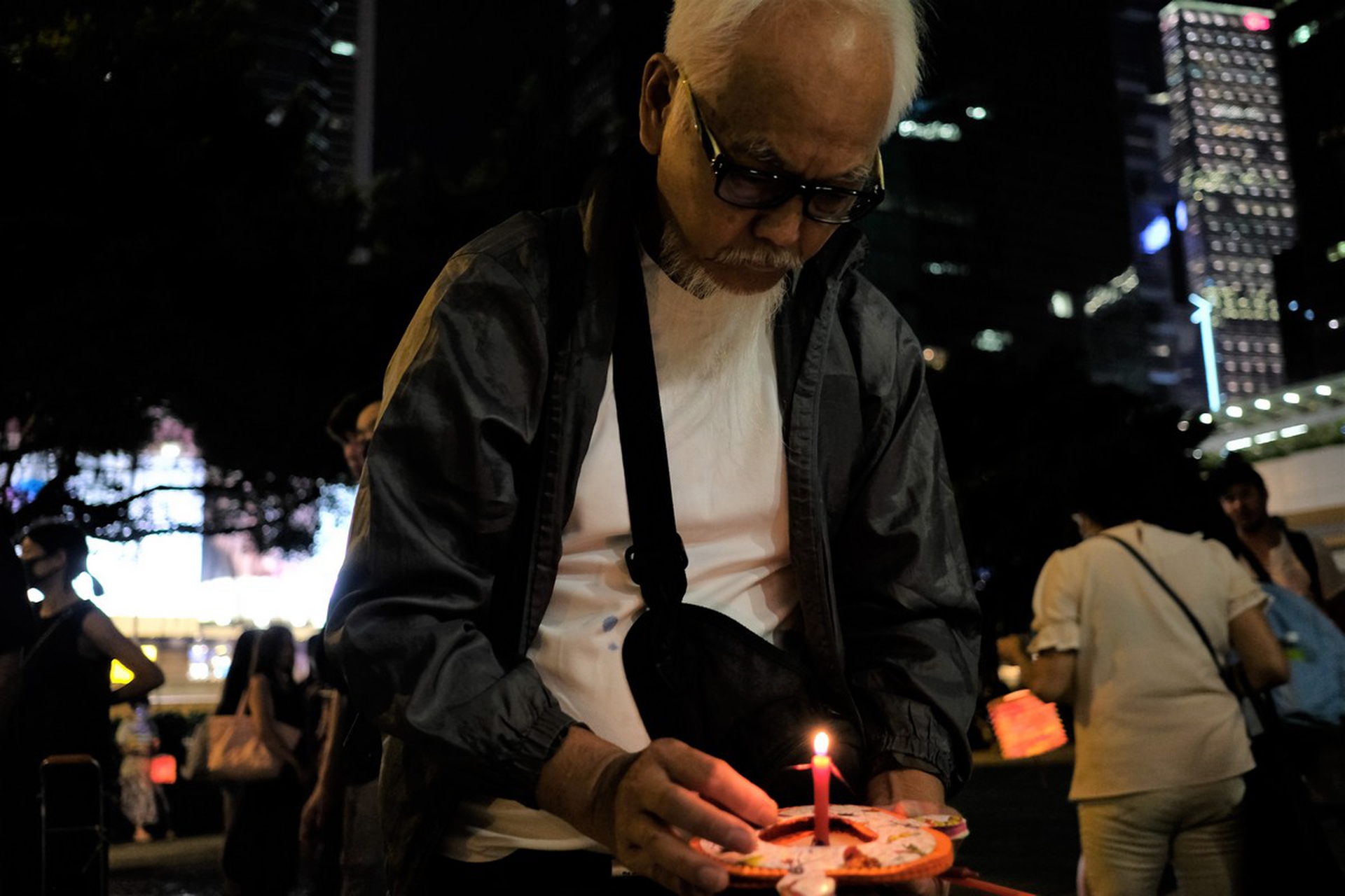 Un uomo prepara una lanterna di fronte Admirality per rendere omaggio a 9 attivisti che si sono sucidati per protestare contro il governo Lam