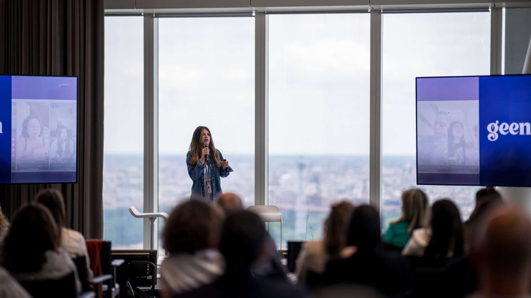 Una delle founder Lucia Vernino presenta Geen.ai durante un workshop davanti a un pubblico, con il logo della startup proiettato sugli schermi.