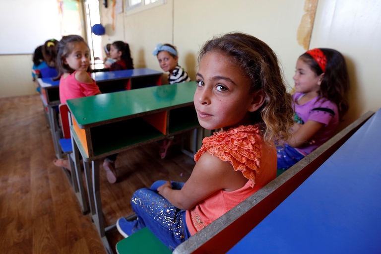 Bambini seduti davanti ai banchi di scuola nel campo profughi di al-Rahma, Siria.