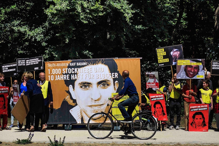 BERLIN, GERMANY - JUNE 11:  A cyclist passes as activists demonstrate outside the Saudi Arabian Embassy against the recent Saudi court ruling that upheld a previous verdict of ten years in prison and 1,000 lashes for Saudi blogger Raif Badawi on June 11, 2015 in Berlin, Germany. The court accuses Badawi of insulting Islam in an Internet forum. (Photo by Carsten Koall/Getty Images)