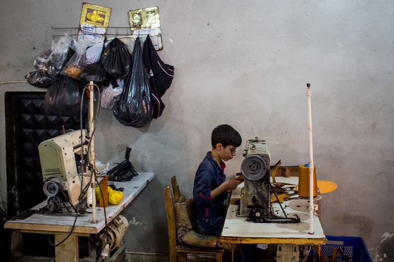 Bambino che lavora alla macchina da cucire
