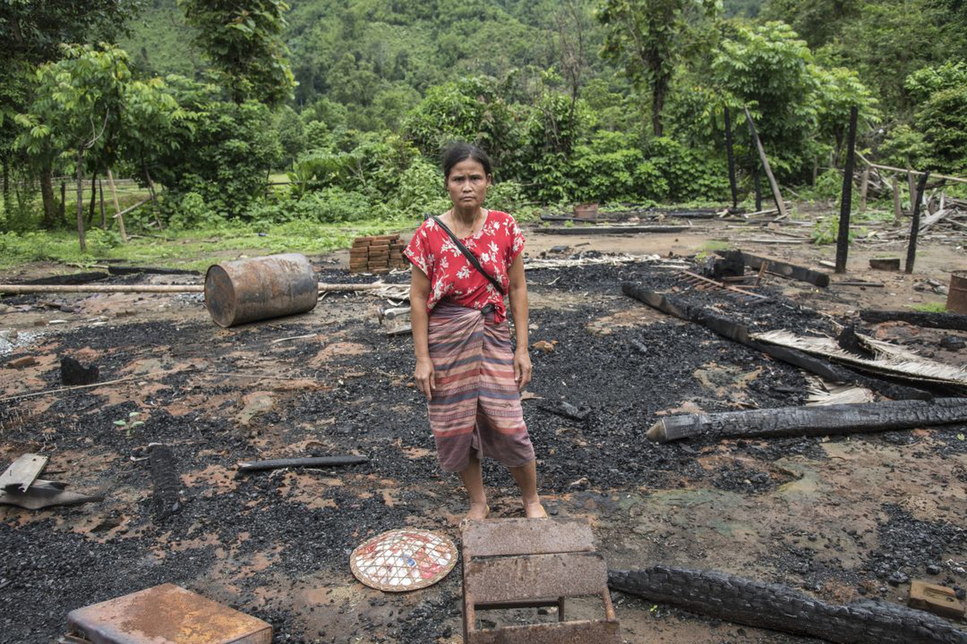 A woman stands in the rubble of her house in Day Pu No that
