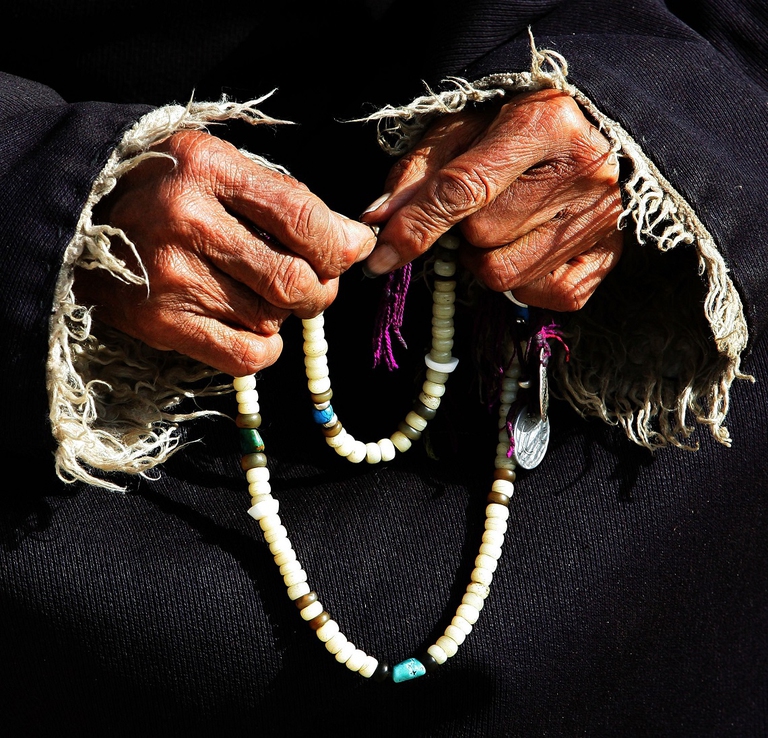 Anziana tibetana rigira tra le mani una sorta di rosario