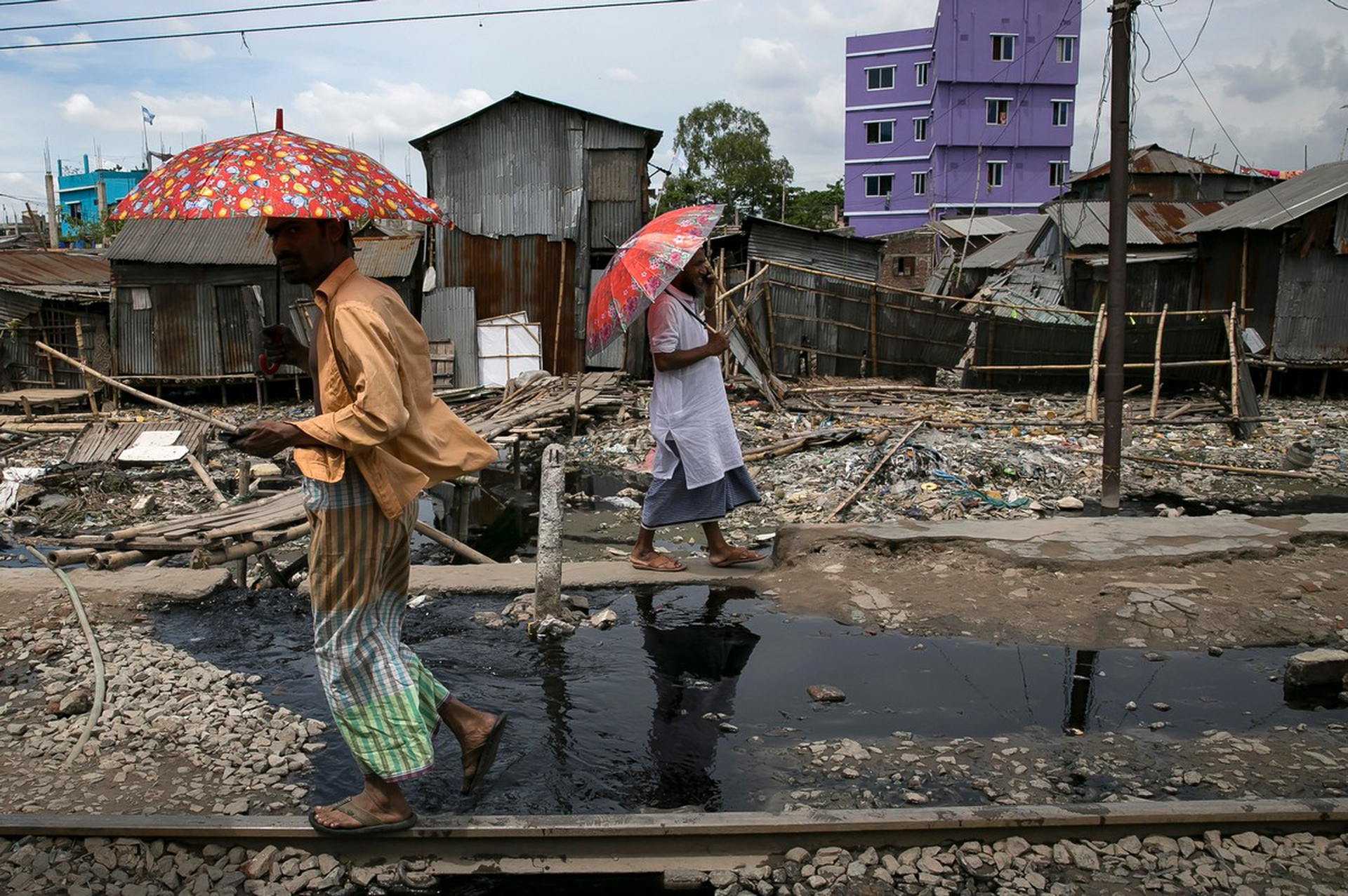 Due persone camminano lungo un fiume inquinato in Bangladesh