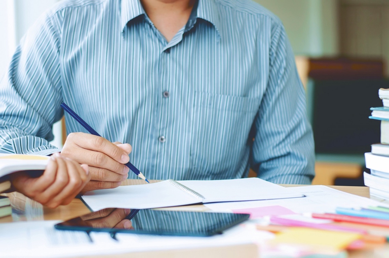 Studente seduto al tavolo che scrive al quaderno