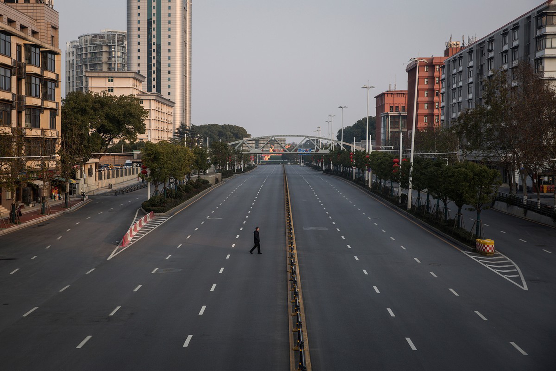 Una persona cammina nelle strade deserte di Wuhan