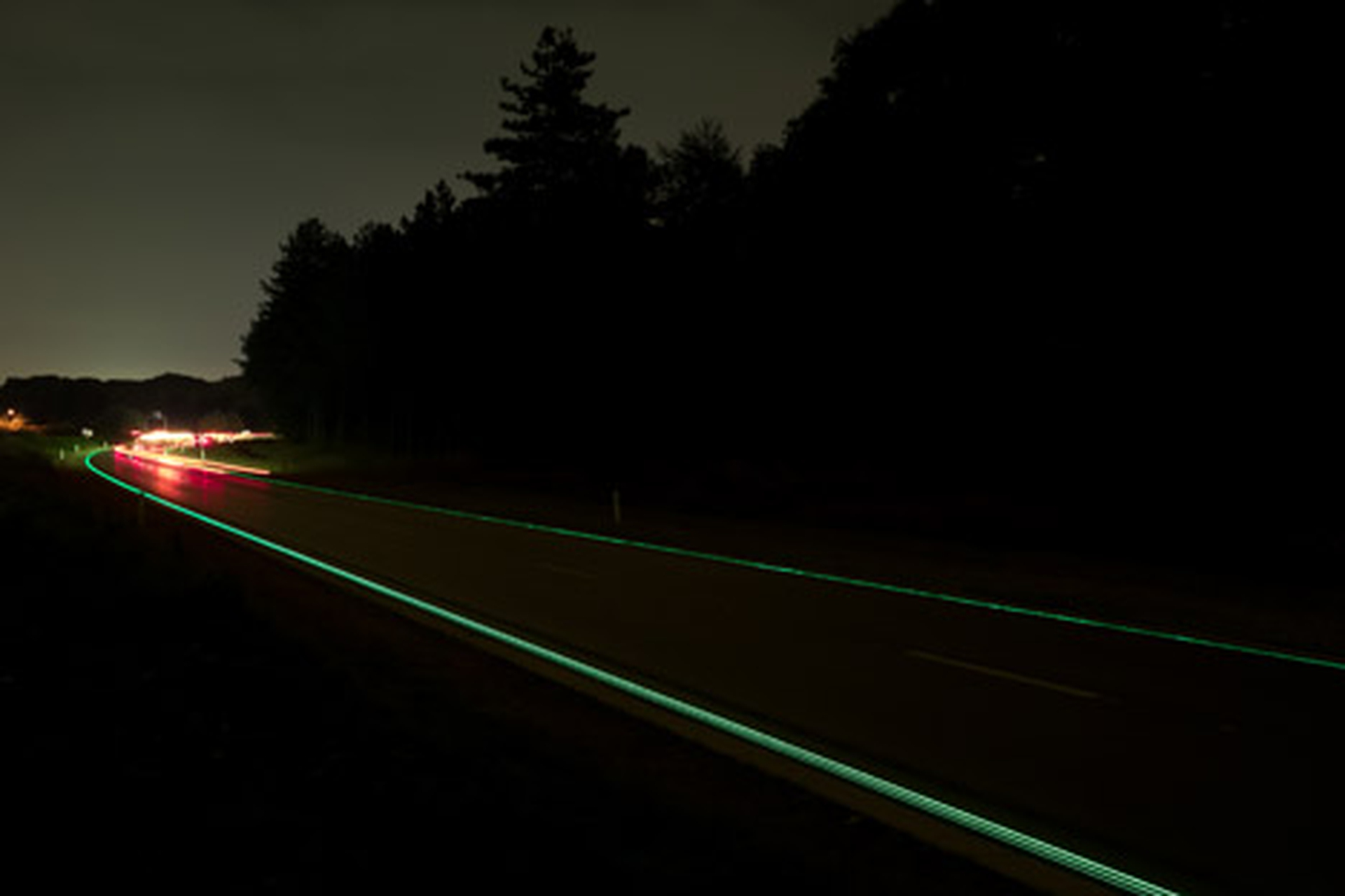 Macchina che passa su autostrade bioluminescenti