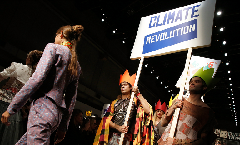 Modelli che sfilano reggendo un cartello che riporta: "Climate Revolution"