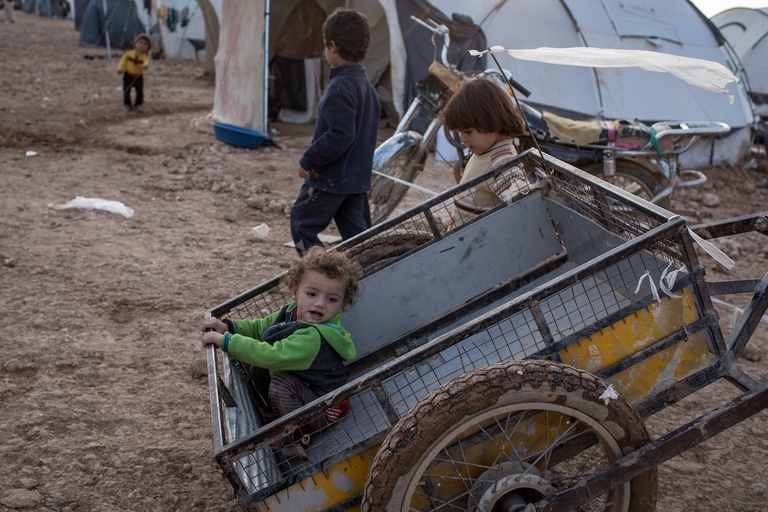 Alcuni bambini in un Campo IDP a Raqqa, Siria, giocano con un carretto di legno.